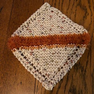 May include: A white knitted dishcloth with a brown and orange sparkly trim.