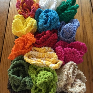 May include: A collection of 14 colorful crocheted dishcloths in a brown wicker basket. The dishcloths are in various colors, including red, orange, yellow, green, blue, and purple.