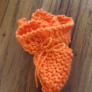 May include: A bright orange knitted dishcloth with a tied string in the center.