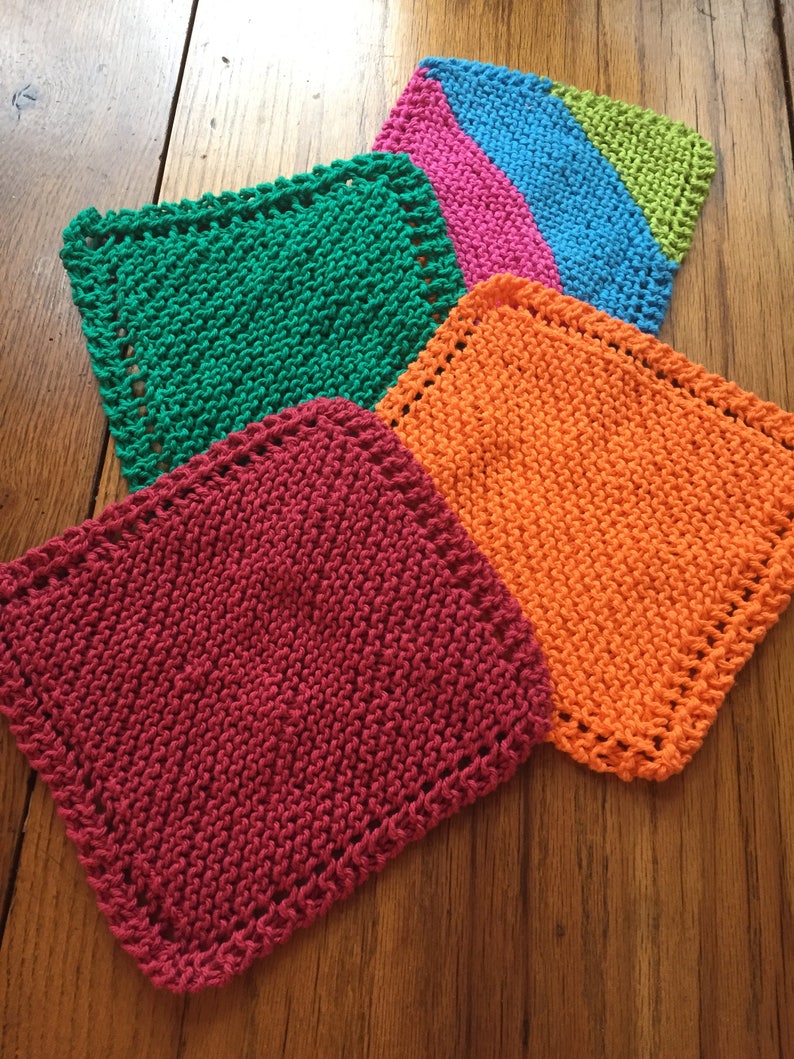 May include: Four knitted dishcloths in different colors: green, pink, orange, and red. The dishcloths are square and have a decorative border.