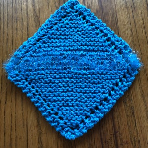 May include: A blue knitted dishcloth with a sparkly blue trim. The dishcloth is square shaped and has a crocheted border.