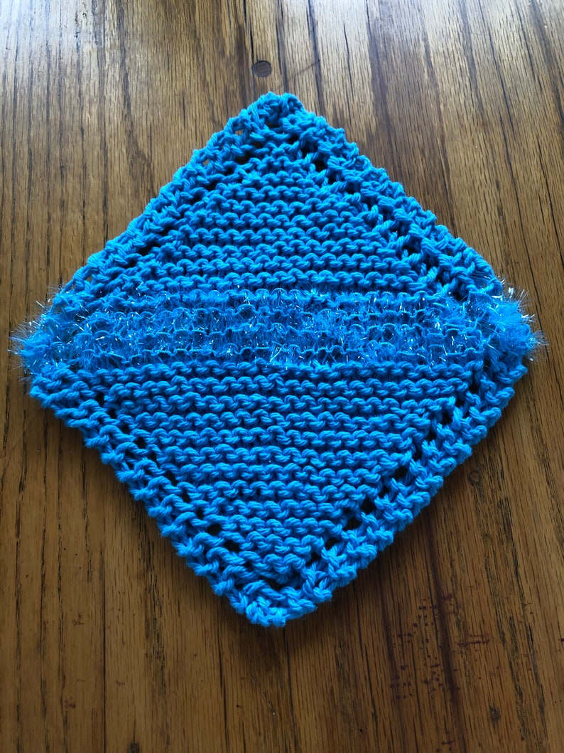 May include: A blue knitted dishcloth with a sparkly blue trim. The dishcloth is square shaped and has a crocheted border.