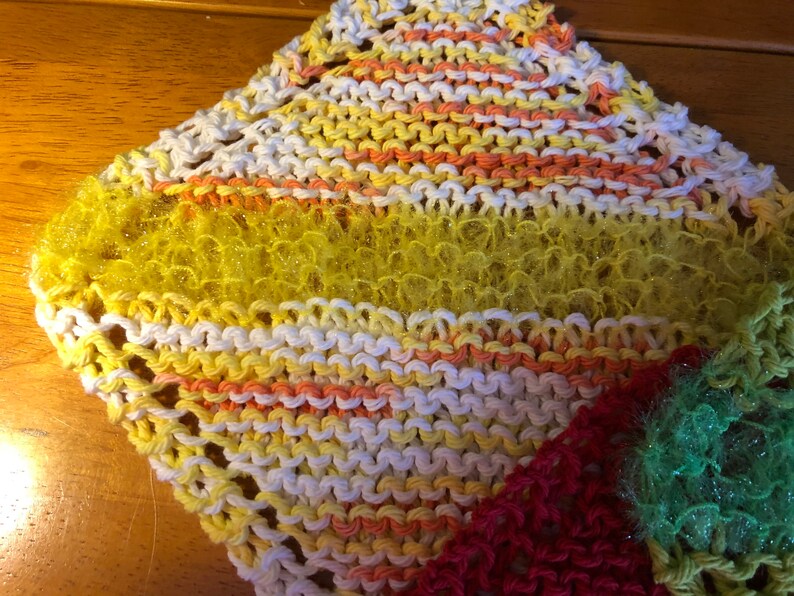 May include: A multi-colored knitted dishcloth with a yellow, orange, and white striped pattern. The dishcloth has a textured, fluffy surface.