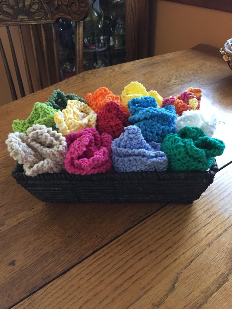 May include: A basket filled with colorful crocheted dishcloths in various shades of green, yellow, orange, red, pink, blue, and white.