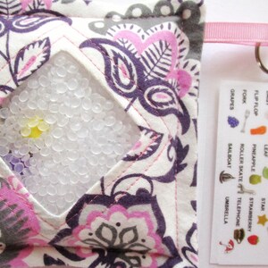May include: A white fabric pouch with a pink floral pattern and a clear plastic window filled with small white beads. The pouch has a pink ribbon with a silver key ring attached. A white card with a list of items to find is attached to the pouch.