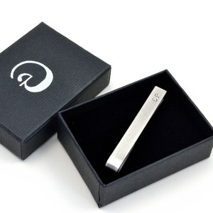 Oxidised Sterling silver tie clip shown in elegant black gift box with black interior as it will arrive when purchased. Box has simple logo in silver on front and fits the tie clip perfectly. Tie clip is shown personalised with initials on front.
