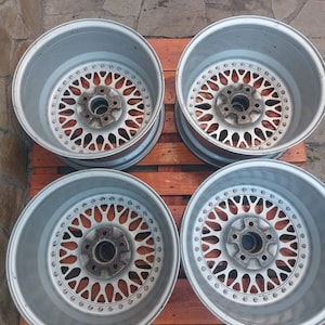 Puede incluir: Cuatro llantas de aleaci&oacute;n de plata para coche con un dise&ntilde;o de radios m&uacute;ltiples. Las ruedas tienen un patr&oacute;n circular de peque&ntilde;os agujeros alrededor del centro y est&aacute;n sobre una superficie de madera. Las ruedas est&aacute;n dise&ntilde;adas para un coche.