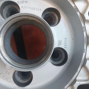 Puede incluir: Primer plano de una llanta de coche plateada con m&uacute;ltiples orificios para pernos. La llanta tiene el texto "GERMANY" y "RS 262" impreso. El centro de la rueda tiene una gran abertura circular.