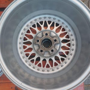 Puede incluir: Una llanta de coche plateada con un dise&ntilde;o de m&uacute;ltiples radios. La llanta tiene una llanta circular con una serie de peque&ntilde;os pernos alrededor del borde. El centro de la llanta presenta un cubo con m&uacute;ltiples orificios para pernos.