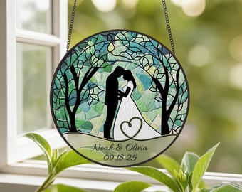 May include: Round stained glass wedding decoration featuring a silhouette of a couple under a tree, with a heart and the names "Noah & Olivia" and the date "09.18.25". The background is a mosaic of green and blue glass.