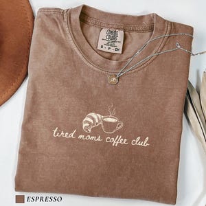 Aesthetic mom tee with tired moms coffee club phrase and subtle coffee illustration in minimalist style