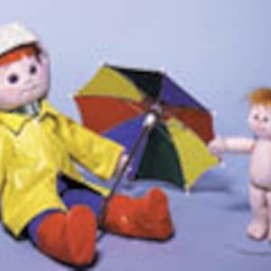 May include: Two red-haired dolls, one wearing a yellow raincoat, red boots, and a white hat, holding a multi-colored umbrella, and the other doll is naked.