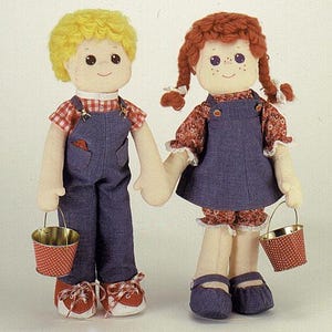 May include: Two handmade rag dolls, a boy and a girl, holding hands. The boy doll has yellow hair, a red and white plaid shirt, and blue dungarees. The girl doll has red braids, a floral print top, and a blue denim pinafore. Each doll holds a red and white polka dot bucket.