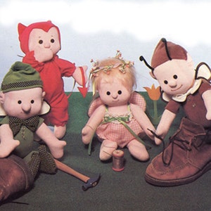 May include: A whimsical scene featuring four handmade fabric dolls. One doll is dressed as a devil in red, another as an elf in green, a fairy in pink, and a bug-like character in brown. They are posed with a shoe, hammer, and thread.