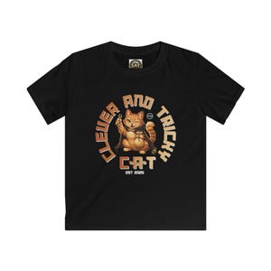 May include: Black t-shirt featuring a cartoon cat with a key, surrounded by the words "CLEVER AND TRICKY CAT" in a circular design. The cat is orange and brown, winking and holding a key. The text "EST 2023" is below the cat.