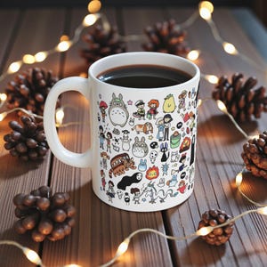 Close-up view of a cute anime mug with forest spirit and Kodama inspired illustration. Nature-themed coffee mug influenced by the magical worlds of Princess Mononoke and My Neighbor Totoro with detailed kawaii character artwork.