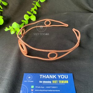 May include: A copper-colored metal headband featuring a twisted wire design with three circular accents. The headband displays the text VIET TENSOR. Below it, a blue card reads THANK YOU For choosing VIET TENSOR, WhatsApp +84977386811, www.etsy/shop/viettensorstore.