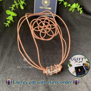 May include: A copper-colored wire pendant featuring a geometric flower-of-life pattern and a clear, faceted crystal point wrapped in wire. The piece includes a matching copper-colored cord. Text on the image reads: VIET TENSOR and GIFT for you.