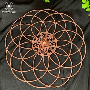 Puede incluir: Arte mural geométrico de color cobre con una esfera central. El diseño presenta círculos entrelazados, creando un patrón simétrico. El texto "VIET TENSOR" es visible en la esquina superior izquierda. La obra de arte se muestra sobre un fondo oscuro y texturizado.