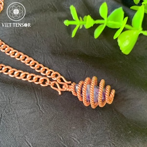 May include: A copper-coloured necklace featuring a spiral pendant holding a purple gemstone. The chain is made of thick, interlocking links. The text "VIET TENSOR" is visible in the upper left corner.