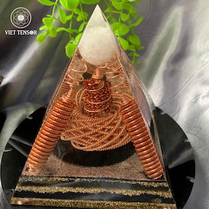 May include: A clear resin pyramid with copper wire and a white sphere at the top. The pyramid has a black base with gold accents and the text "VIET TENSOR" in the upper left corner.