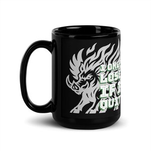 以下が含まれることがあります： 黒いセラミックマグカップ。白いと緑色のイノシシのグラフィックと「I Only Lose If I Quit」のテキストが特徴です。マグカップは黒いハンドルと光沢のある仕上げです。
