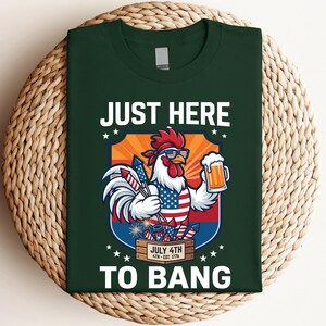 Man holding a beer at a July 4th BBQ wearing the funny just here to bang rooster shirt.