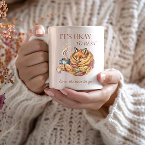 Cozy fox autumn mug in high-quality white ceramic, perfect for coffee, tea, or hot chocolate. Illustrated fox surrounded by autumn leaves, cottagecore and hygge style. A thoughtful gift for women or men, animal lovers, and woodland enthusiasts. Unique illustrated mug, durable, dishwasher and microwave safe, perfect for cozy fall vibes or as a seasonal gift idea for fox lovers and autumn home décor.