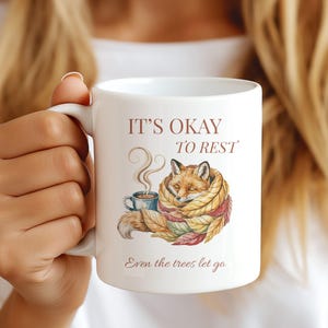 Cozy fox autumn mug in high-quality white ceramic, perfect for coffee, tea, or hot chocolate. Illustrated fox surrounded by autumn leaves, cottagecore and hygge style. A thoughtful gift for women or men, animal lovers, and woodland enthusiasts. Unique illustrated mug, durable, dishwasher and microwave safe, perfect for cozy fall vibes or as a seasonal gift idea for fox lovers and autumn home décor.