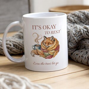 Cozy fox autumn mug in high-quality white ceramic, perfect for coffee, tea, or hot chocolate. Illustrated fox surrounded by autumn leaves, cottagecore and hygge style. A thoughtful gift for women or men, animal lovers, and woodland enthusiasts. Unique illustrated mug, durable, dishwasher and microwave safe, perfect for cozy fall vibes or as a seasonal gift idea for fox lovers and autumn home décor.