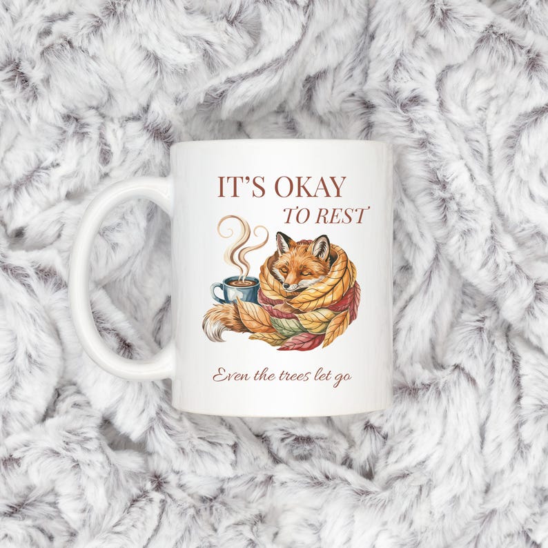 Cozy fox autumn mug in high-quality white ceramic, perfect for coffee, tea, or hot chocolate. Illustrated fox surrounded by autumn leaves, cottagecore and hygge style. A thoughtful gift for women or men, animal lovers, and woodland enthusiasts. Unique illustrated mug, durable, dishwasher and microwave safe, perfect for cozy fall vibes or as a seasonal gift idea for fox lovers and autumn home décor.