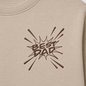 Può includere: Felpa beige con la scritta ricamata "BEST DAD" in marrone in stile fumetto. La felpa ha un girocollo e una vestibilità rilassata.