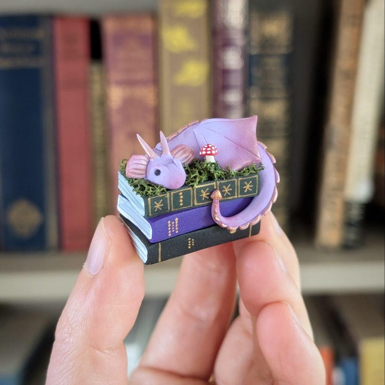 Figura de dragón de libro de fantasía, decoración de escritorio o compañero de estantería en color lavanda, verde o dorado, estatuilla de arcilla polimérica hecha a mano de 3,5 cm. Morado