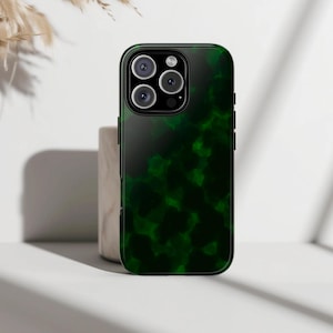 Puede incluir: Funda de teléfono verde oscuro con un patrón moteado. La funda tiene un acabado brillante y un borde negro. Las lentes de la cámara son visibles en la parte superior. La funda está diseñada para proteger el teléfono.