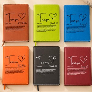 May include: Six rectangular notebooks in brown, lime green, blue, orange, black, and maroon. Each cover features the word Team, a heart icon, a name, and a dictionary-style definition printed in black text. The notebooks have stitched edges.