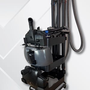 May include: A black and gray commercial cleaning cart with multiple attachments. The cart has a vacuum cleaner, a gray water tank, and various cleaning tools. The cart is on wheels for easy maneuverability. The design is functional and professional.