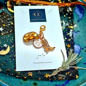 May include: Gold-colored charm set featuring a cowboy hat, a cowboy boot, and a circular charm with the letter "H". The charms are attached to a clasp. A white card with the text "CHARMS FOR ROSES" and "CharmsforRoses.etsy.com" is in the background.