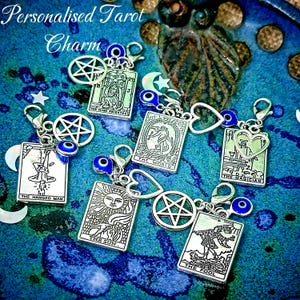 May include: Silver-toned tarot card charms with various designs, including The Sun, The Fool, and The High Priestess. Each charm has a clasp, a blue evil eye bead, and a decorative element. The text "Personalised Tarot Charm" is at the top.