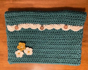 May include: Teal crochet pouch with a white scalloped trim and three wooden buttons. The pouch is decorated with three small crochet flowers in white and yellow. This handmade item is perfect for storing small items.