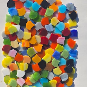 May include: A collection of colorful, fan-shaped glass mosaic tiles in various shades of orange, yellow, green, blue, red, black, and white. The tiles are arranged closely together, creating a vibrant and textured surface. Ideal for craft projects.