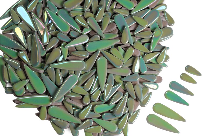 May include: A collection of iridescent, teardrop-shaped glass beads in shades of green, olive, and brown. The beads have a glossy finish and are scattered across a white background. The beads vary in size and are suitable for jewelry making or craft projects.