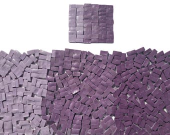 May include: A mosaic tile design in shades of purple. The image features a square tile arrangement above a larger, wave-like arrangement of tiles. The tiles are small, rectangular, and have a textured appearance.