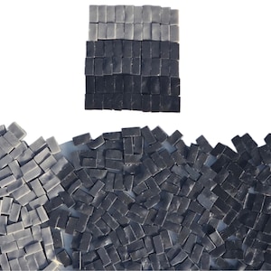 May include: An abstract composition featuring small, rectangular tiles in shades of gray and black. The tiles are arranged in a gradient pattern, with a rectangular block at the top and a wave-like formation at the bottom. The tiles are likely made of stone or a similar material.