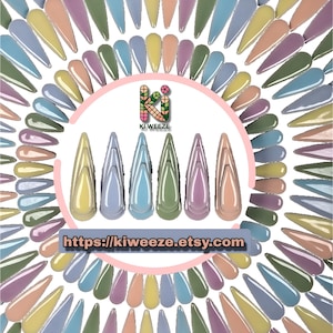 May include: A collection of pastel-colored, long, pointed artificial nails arranged in a circular pattern. The colors include shades of yellow, peach, lavender, green, and blue. The text "KI WEEZE" and a website address are also visible.