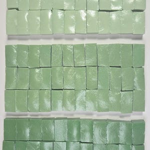 May include: Rows of rectangular, light green tiles arranged in a grid pattern. The tiles vary in shade, creating a gradient effect from light to dark green. The tiles have a glossy finish, reflecting light.