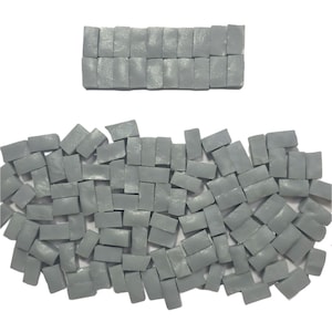 May include: A collection of small, rectangular, gray tiles scattered on a white background. Some tiles are arranged in a neat row at the top. The tiles have a slightly textured surface and a matte finish, suggesting they are for mosaic art or crafts.
