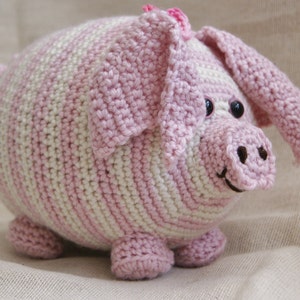 Könnte beinhalten: Ein rosa-weiß gestreiftes Häkelspielzeug in Form eines Schweins mit schwarzen Augen und einer rosa Schnauze.