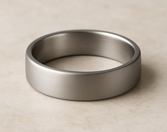 May include: A solid band ring with a brushed matte finish in a neutral grey metallic tone. The ring features a simple, smooth, and circular design with a consistent width throughout, showcasing a clean and understated appearance.