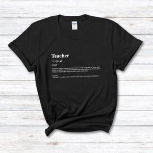 Pode incluir: Camiseta preta com a palavra "Teacher" e uma definição de dicionário em branco. A definição inclui a pronúncia, a classe gramatical e uma frase de exemplo. Um presente divertido para professores.