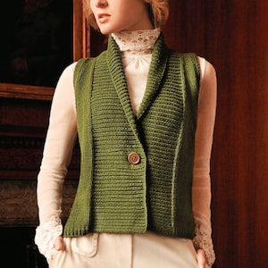 Może przedstawiać: Zielona dzianinowa kamizelka z kołnierzem szalowym i zapięciem na jeden guzik. Kamizelka jest noszona na białej bluzce i połączona z kremowymi spodniami. Obraz zawiera logo "blue sky alpacas".